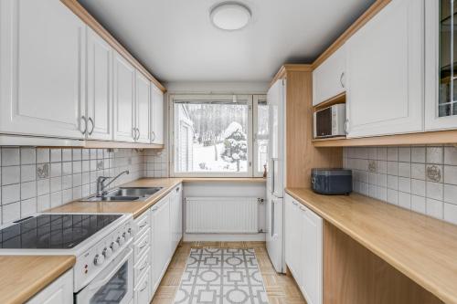 a kitchen with white cabinets and a window at Private rooms near metro, free parking in Helsinki
