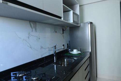 クイアバにあるBrisas Flat Hotelのシンクと冷蔵庫付きのキッチン