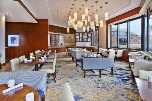 a dining room with tables and chairs and windows at Hilton Garden Inn Portland Downtown Waterfront in Portland