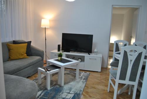 a living room with a couch and a tv and chairs at Apartments FAMILY & FRIENDS -free parking in Sarajevo