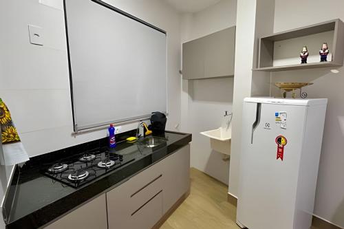 a white kitchen with a stove and a refrigerator at Portofino Apart Hotel Praça do Mercado in Divinópolis