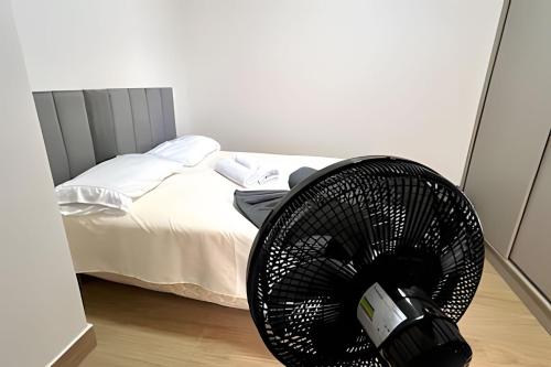 a black fan in a bedroom next to a bed at Portofino Apart Hotel Praça do Mercado in Divinópolis