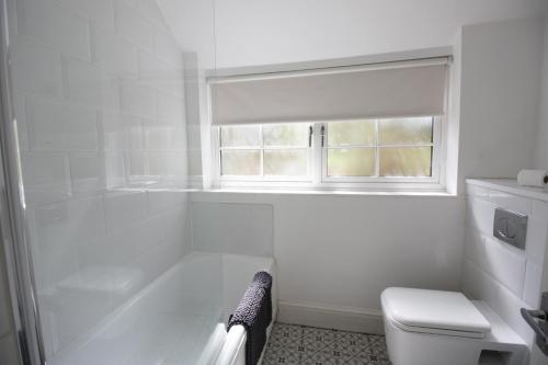 baño con bañera, aseo y ventana en Exceptionally Stunning Four Bed Terraced House With Two Bathrooms- Recently Renovated en Spon End
