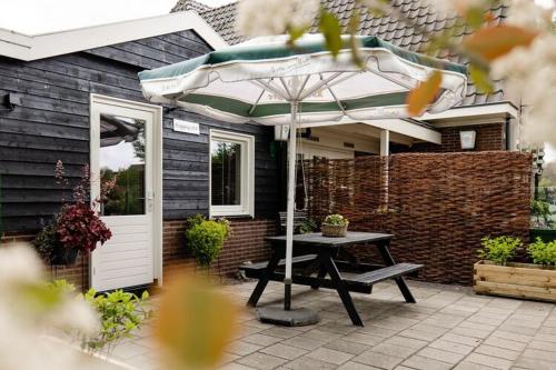 - une table de pique-nique avec un parasol en face d'une maison dans l'établissement Charming house with garden in rural area Hellendoorn, à Hellendoorn