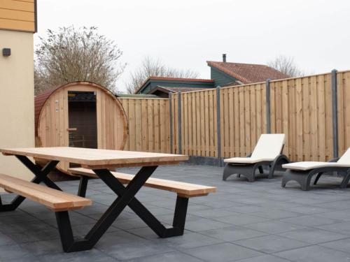 a picnic table and chairs on a patio with a fence at Holiday Home in Zevenhuizen with Sauna Bubble Bath in Zevenhuizen