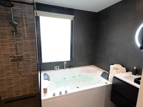 een badkamer met een groot bad en een raam bij Wellness Bungalow with whirlpool and sauna in Zevenhuizen