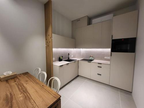 una cucina con armadi bianchi e tavolo in legno di Apartament na wydmie a Mrzeżyno
