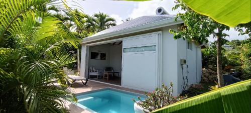 a small house with a swimming pool next to a building at Soley Bungalows Carambole 2 pers Adult only in Sainte-Anne