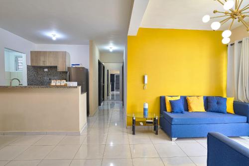 sala de estar con sofá azul y pared amarilla en Terraza del este apto en La Romana