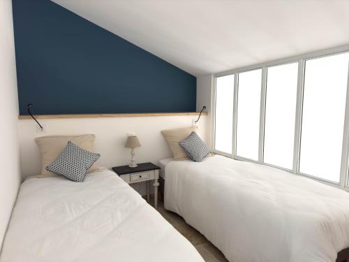 two beds in a room with blue walls and windows at Les suites du 13 in Aigues-Mortes