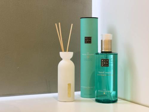 a white vase with sticks in it next to a bottle at Les suites du 13 in Aigues-Mortes