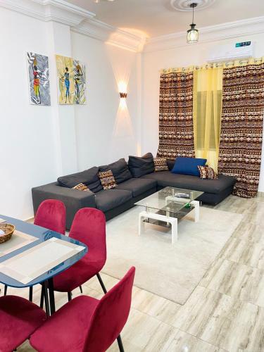 uma sala de estar com um sofá preto e cadeiras vermelhas em Bel appartement entier 2 chambres em Cotonou