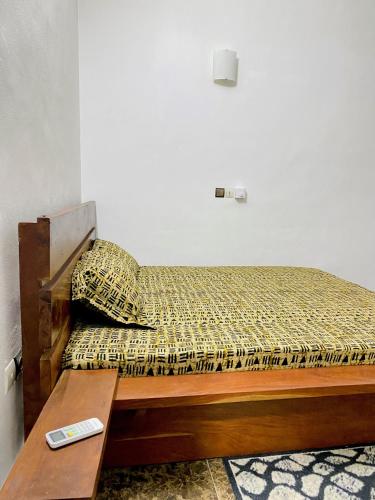 uma cama num quarto com um controlo remoto sobre uma mesa em Bel appartement entier 2 chambres em Cotonou