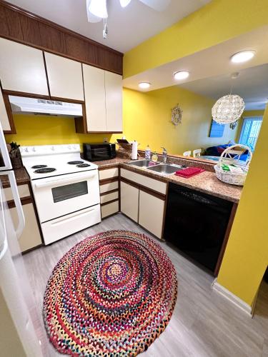 a kitchen with a sink and a rug on the floor at Modern Beachside Bliss: 2 Bed/2 Bath Condo Haven in Rehoboth Beach