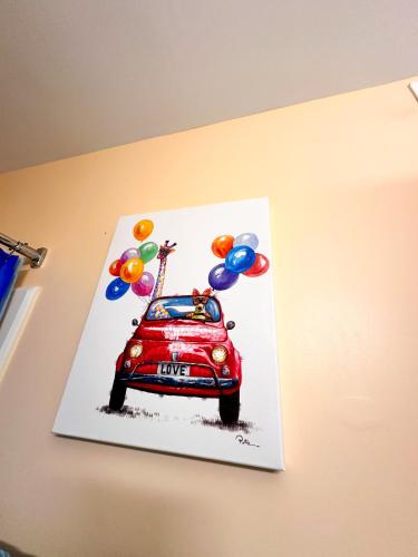 a painting of a red car with balloons on a wall at Modern Beachside Bliss: 2 Bed/2 Bath Condo Haven in Rehoboth Beach