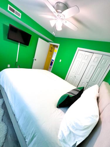 a green bedroom with a white bed and a ceiling fan at Modern Beachside Bliss: 2 Bed/2 Bath Condo Haven in Rehoboth Beach