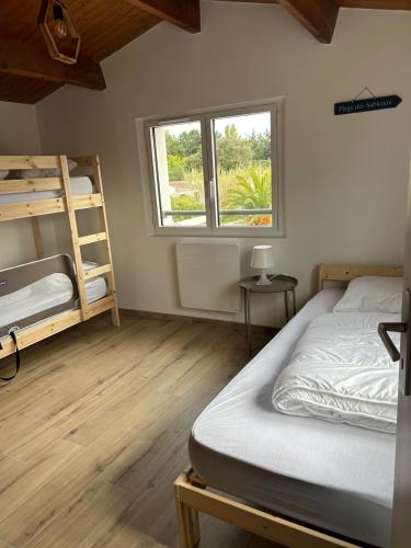 une chambre avec deux lits superposés et une fenêtre dans l'établissement Maison proche de la mer, à Le Grand Vieil