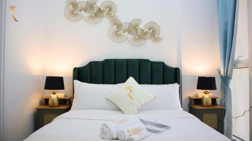 a bedroom with a bed with a green headboard and lamps at Modern City Duplex 2BR apartment in Abu Dhabi
