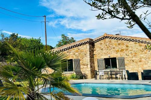 une maison en pierre avec une piscine en face d'un bâtiment dans l'établissement Gîte Le chant des mésanges 07260 Vernon, à Vernon