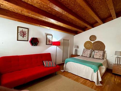 um quarto com um sofá vermelho e uma cama em Casa da Fontiña em Tortoreos
