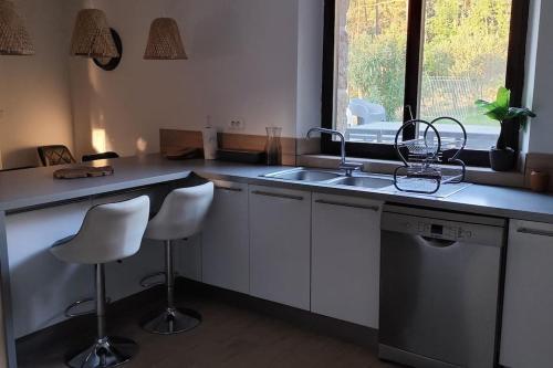 une cuisine avec un évier et un comptoir avec deux tabourets dans l'établissement Gîte Le chant des mésanges 07260 Vernon, à Vernon