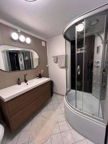 a bathroom with a tub and a shower and a sink at Feriehus med badestamp in Lavik