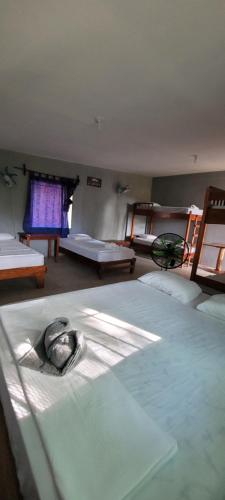 a group of beds in a room with a room with windows at Hostal Xilotl in San José del Sur