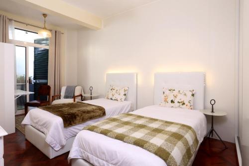 twee bedden in een kleine kamer met witte muren bij Rochinha Cozy Home in Funchal