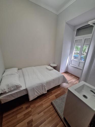 a white bedroom with a bed and a window at Residencial Ideal in Lisbon