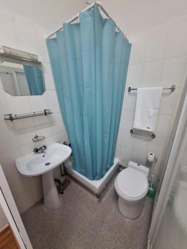 a bathroom with a toilet and a blue shower curtain at Residencial Ideal in Lisbon