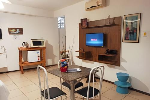 a living room with a table with chairs and a tv at VA Apart Hotel Savassi in Divinópolis