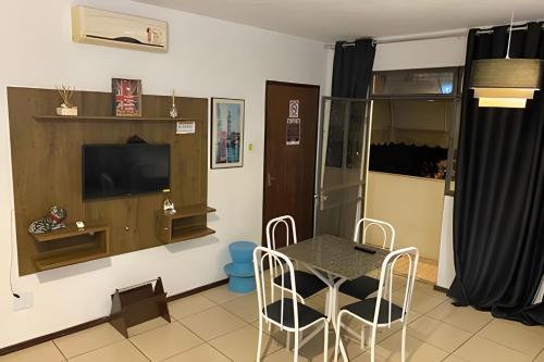a dining room with a table and chairs and a television at VA Apart Hotel Savassi in Divinópolis