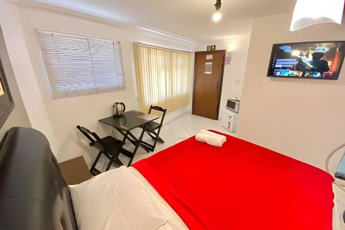 a bedroom with a red blanket on a bed and a table at VA Apart Hotel Savassi in Divinópolis