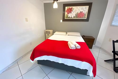a bedroom with a bed with a red and white blanket at VA Apart Hotel Savassi in Divinópolis