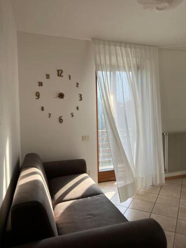 sala de estar con sofá y reloj en la pared en Villa Linfano Isabel, en Nago-Torbole