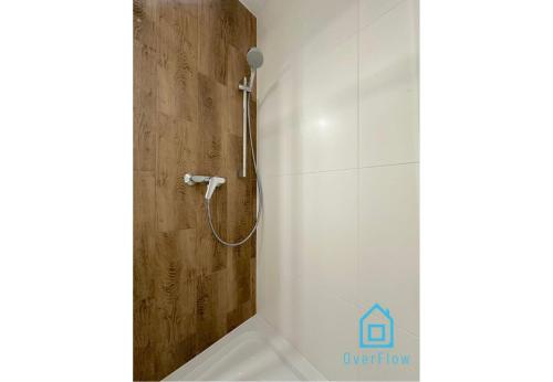 a shower in a bathroom with a wooden wall at Jager Room 10 Min to Old Town Gdańsk,PKP & Shopping Mall in Gdańsk
