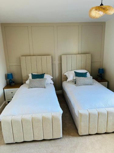 two beds sitting next to each other in a room at Chic seaside apartment in Preston
