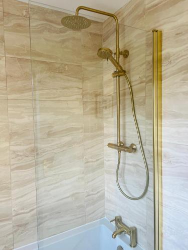 a shower with a glass door and a blue tub at Chic seaside apartment in Preston
