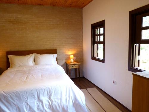 a bedroom with a white bed and two windows at Casa do Aconchego in Gonçalves
