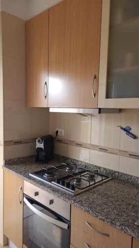a kitchen with a stove and wooden cabinets at Stela ' s Guest House in Loulé