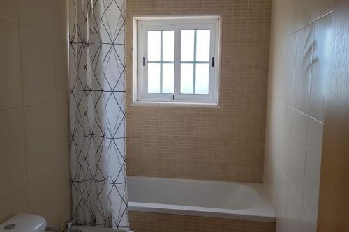 a bathroom with a shower and a tub and a window at Stela ' s Guest House in Loulé