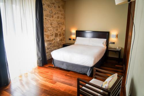 a bedroom with a bed and a table and a chair at Hotel Baeza Monumental by eme hoteles in Baeza