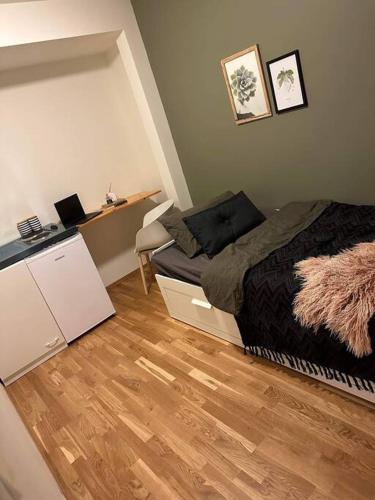 a small bedroom with a bed and a wooden floor at Hybel nær flyplass og kort vei til sentrum in Tromsø