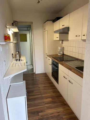 une cuisine avec des armoires blanches et un plancher en bois dans l'établissement Am Fulda-Ufer, à Cassel