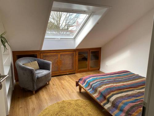 a attic bedroom with a bed and a chair at Reihenhaus mit viel Platz in Hannover