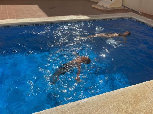 two people are swimming in a swimming pool at Ferienwohnung Torrevieja España in Torrevieja