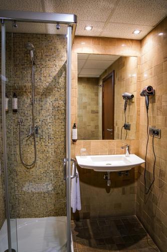 a bathroom with a shower and a sink and a mirror at Hotel Baeza Monumental by eme hoteles in Baeza