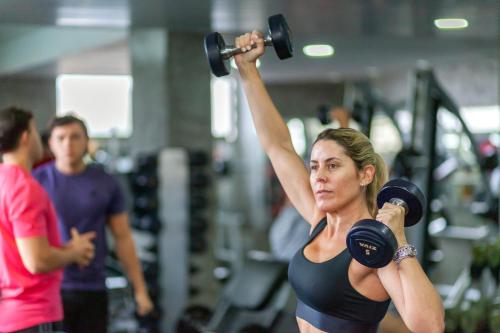 a woman lifting a dumbbell in a gym at Hotel Catalinas Tucuman in San Miguel de Tucumán