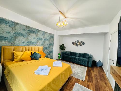 a bedroom with a yellow bed and a couch at Sinuhe Apartment in Braşov