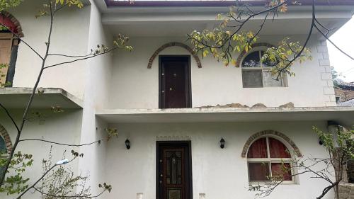 Biały dom z dwoma oknami i drzwiami w obiekcie Bitro House w mieście Pogradec